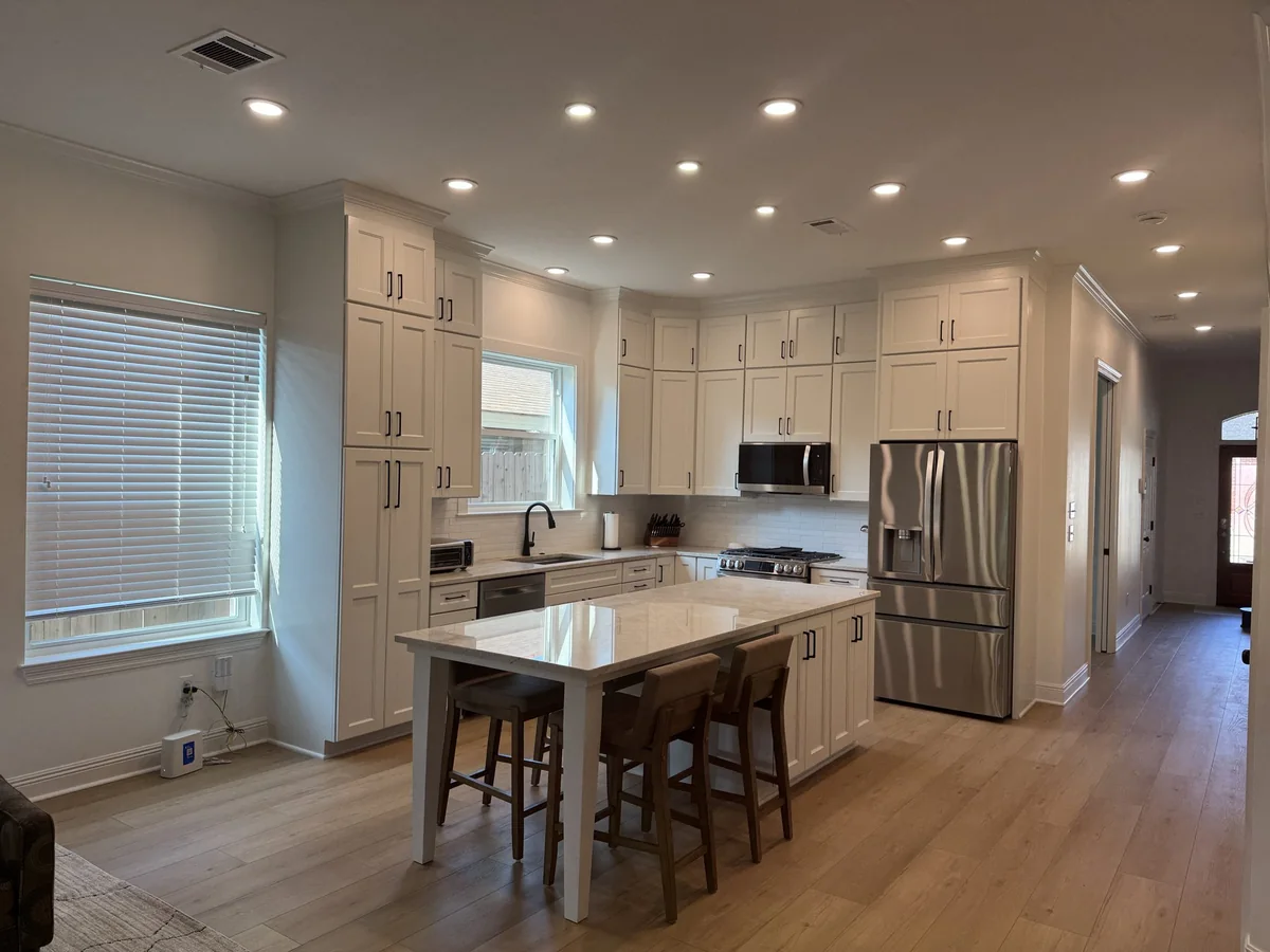 White kitchen with tall cabinetry, stone island and stainless steel appliances