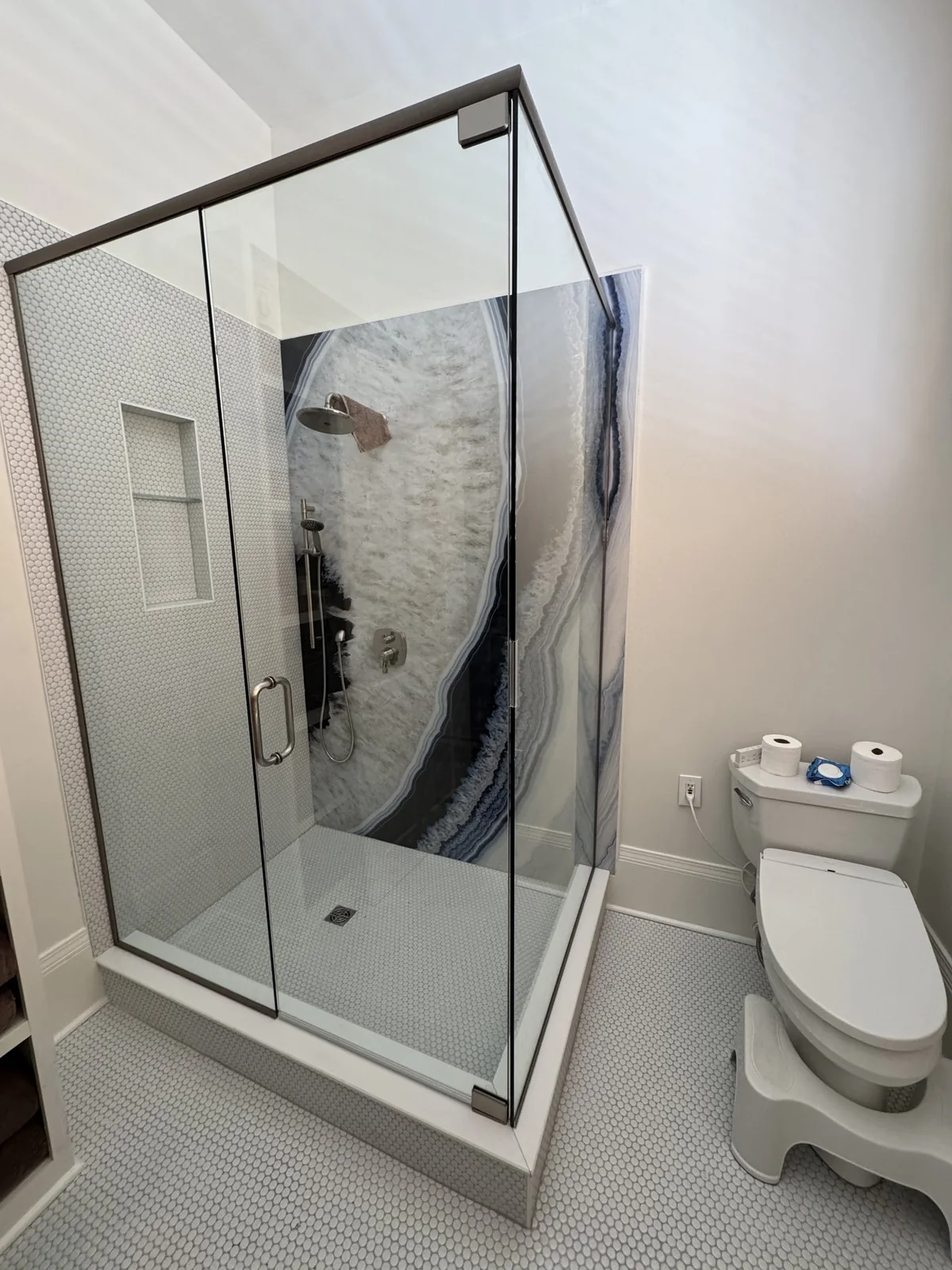 Glass shower with a bold patterned feature wall in the renovated Uptown bathroom.