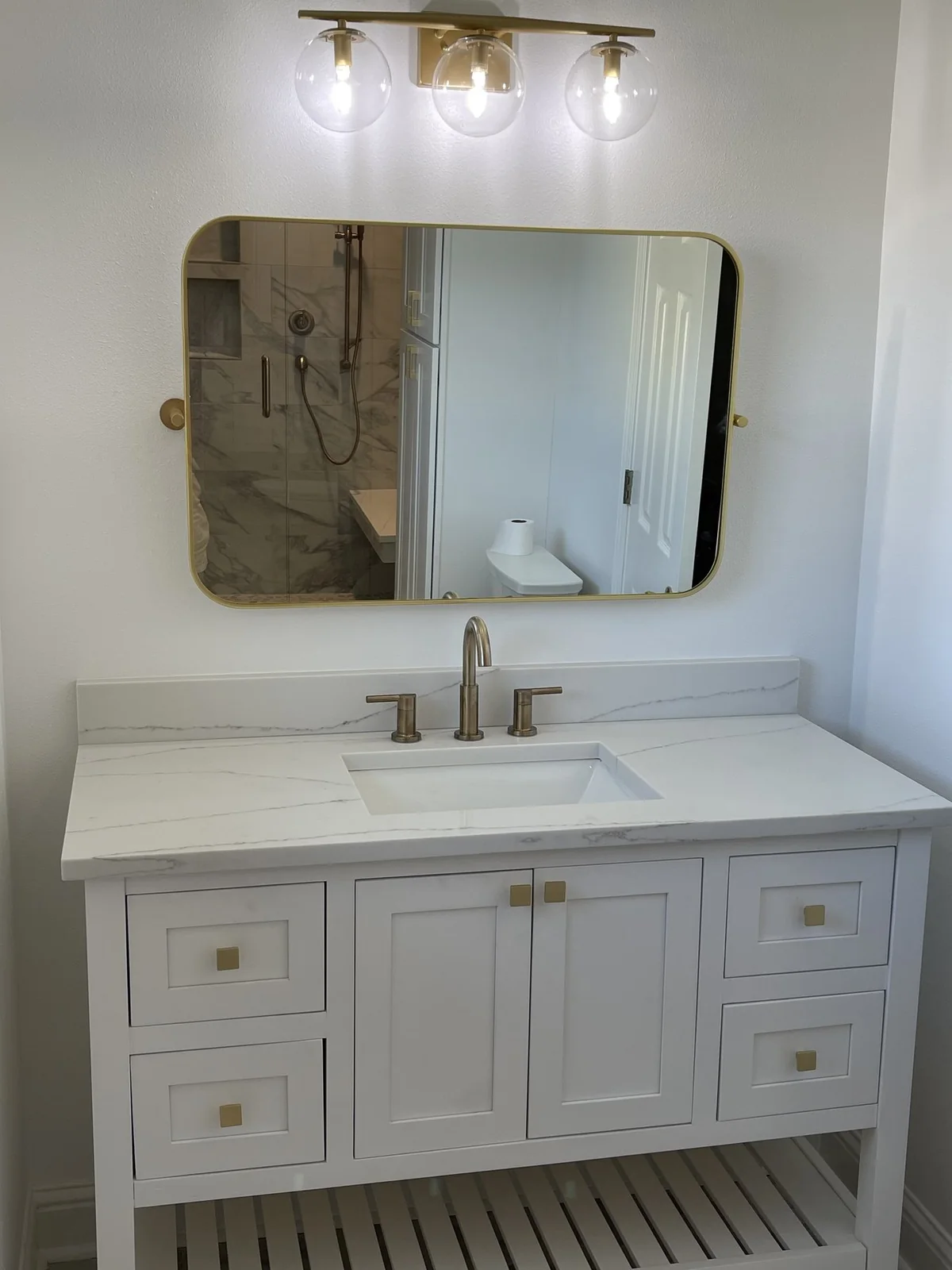 Vanity, mirror, and overhead lighting in the renovated Metairie bathroom.