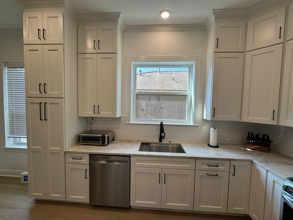 Sink, tall cabinetry, and tile backsplash