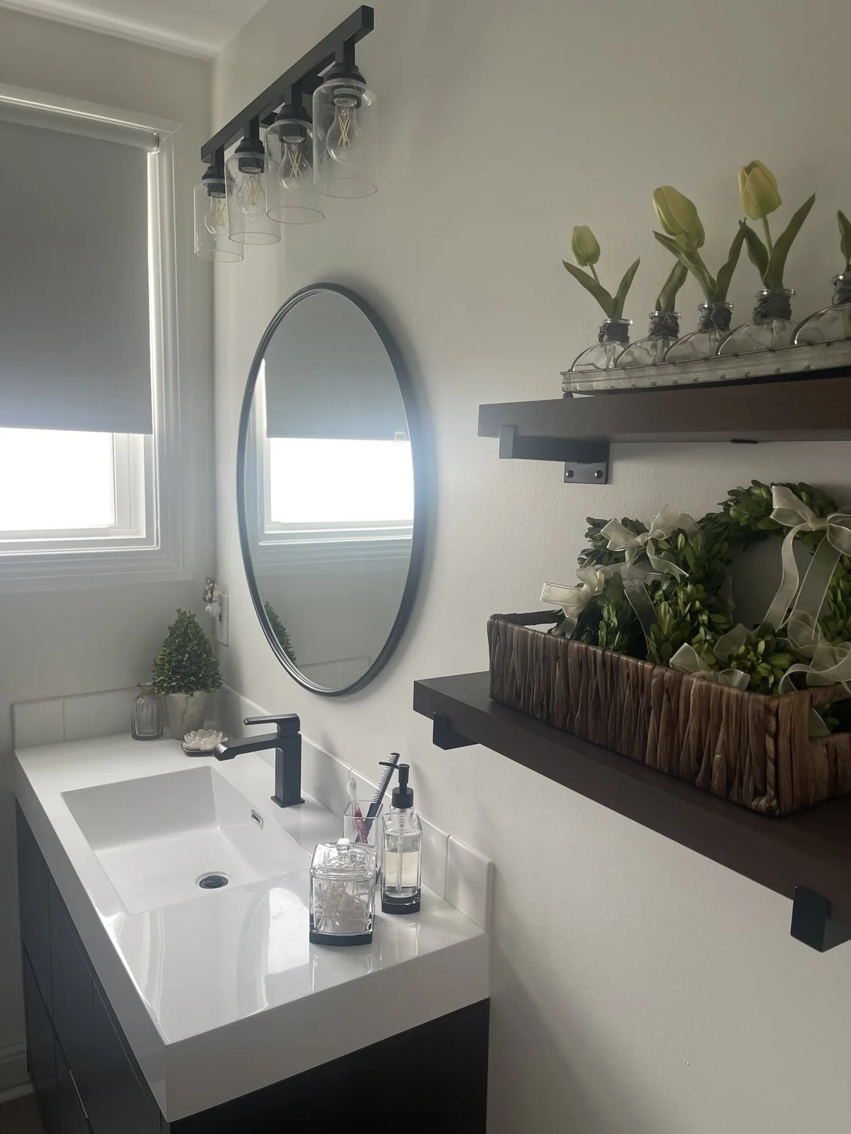 Vanity, round mirror, glass-shade lighting, and wall-mounted shelves.