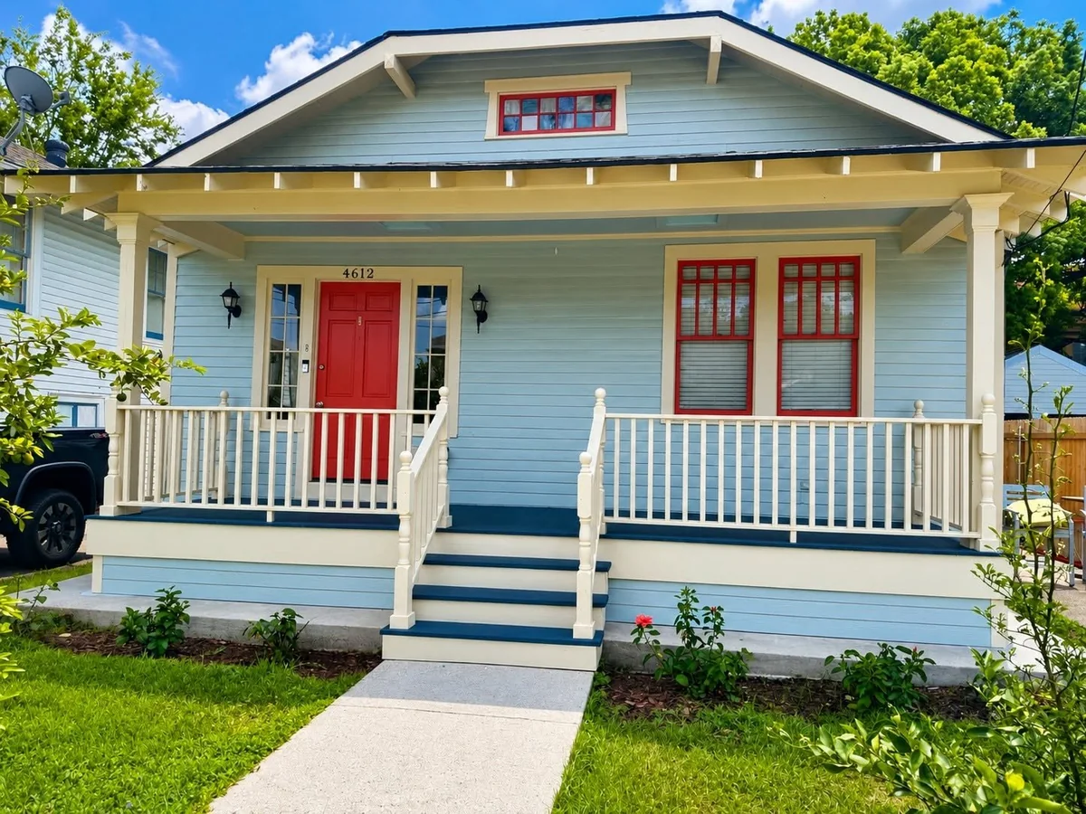 After: raised front porch with white railings, updated steps, and sidelights beside the red front door.
