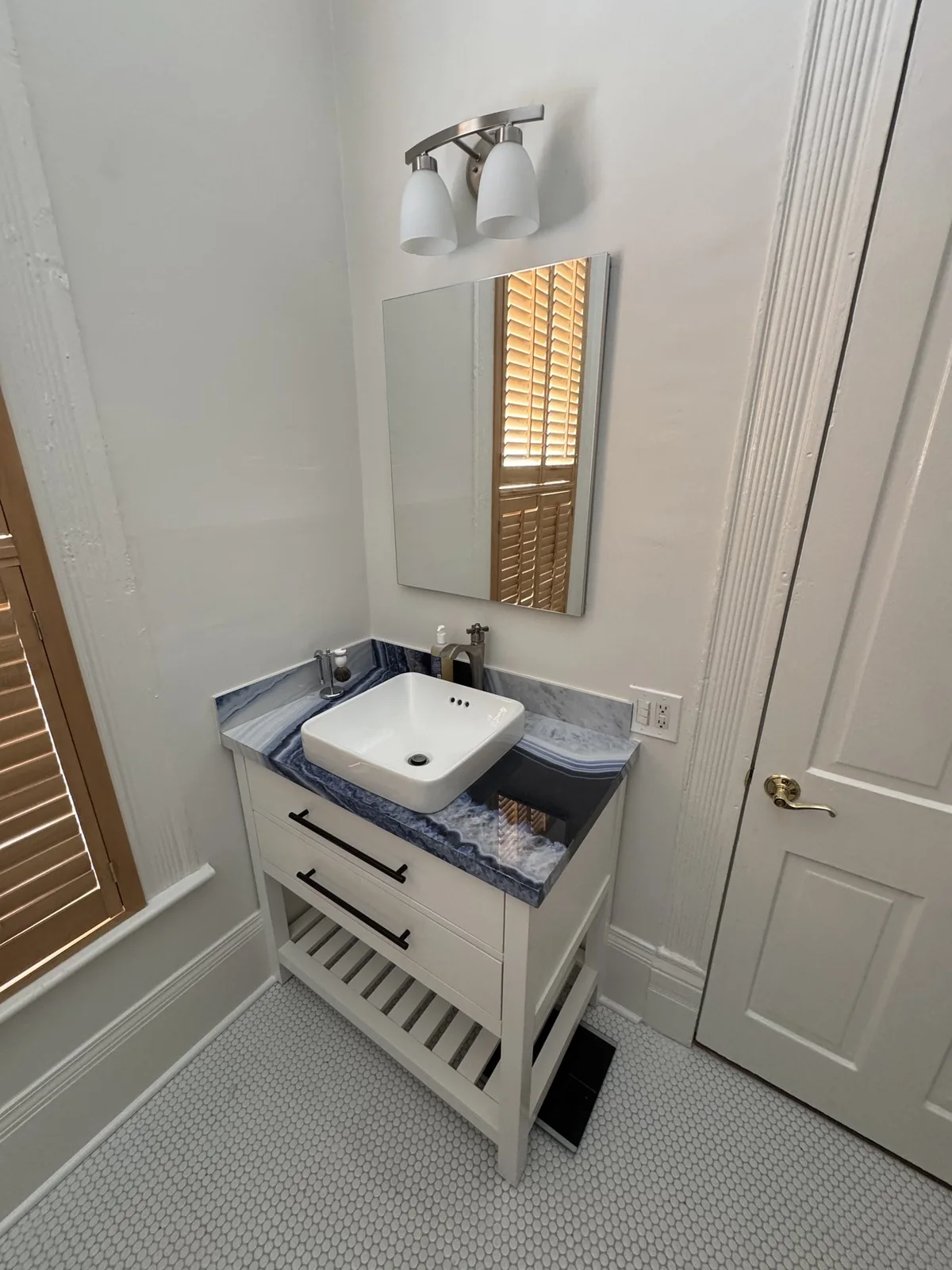 Compact vanity and mirror beside the bathroom window.