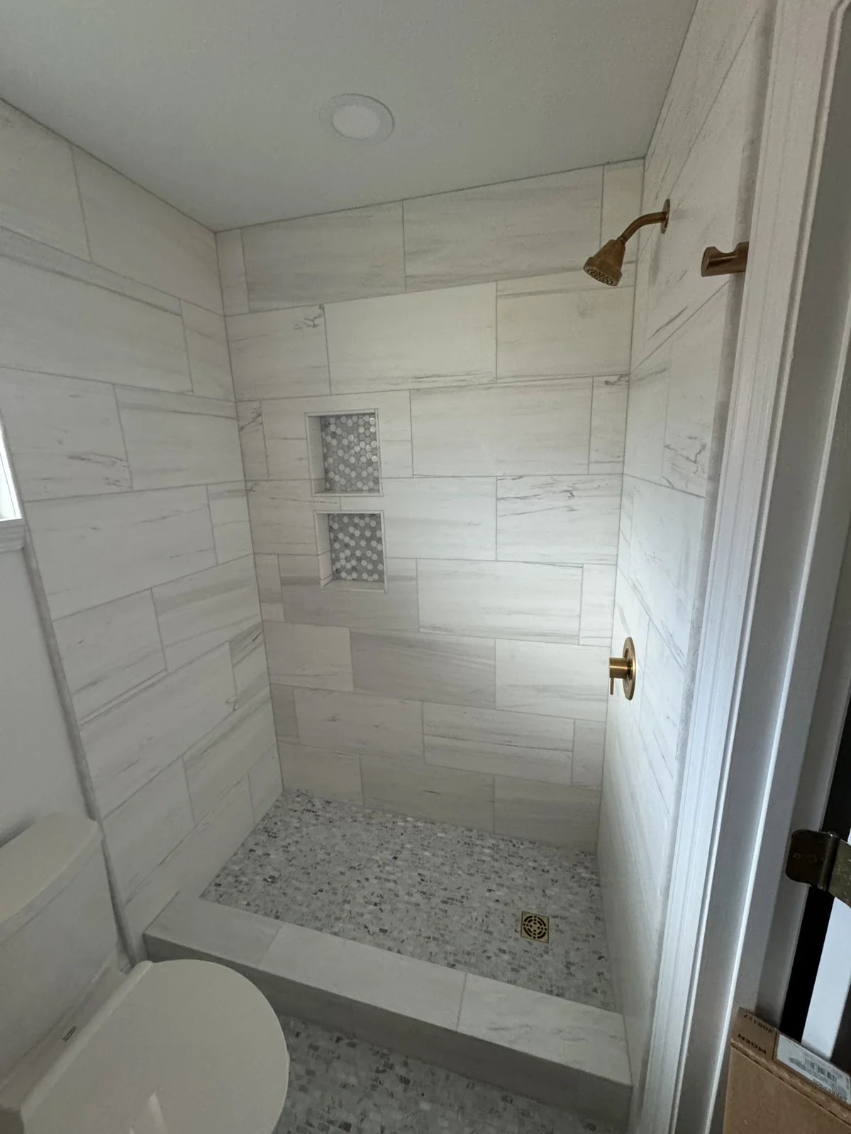 Pale tiled shower with brass fixtures