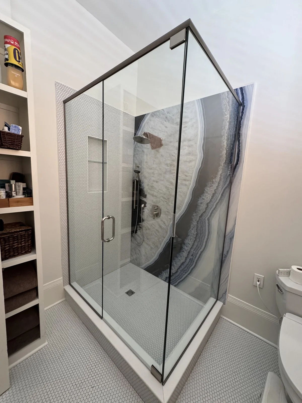 View of the shower enclosure and adjoining bathroom storage.