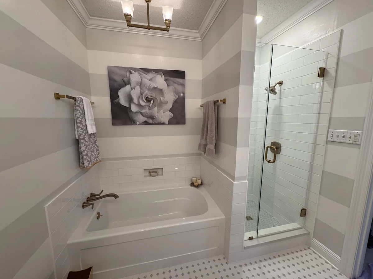Bathroom with a bathtub, glass shower and brass fixtures