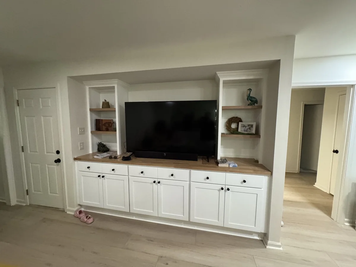 White built-in media cabinets with wood shelves and countertop