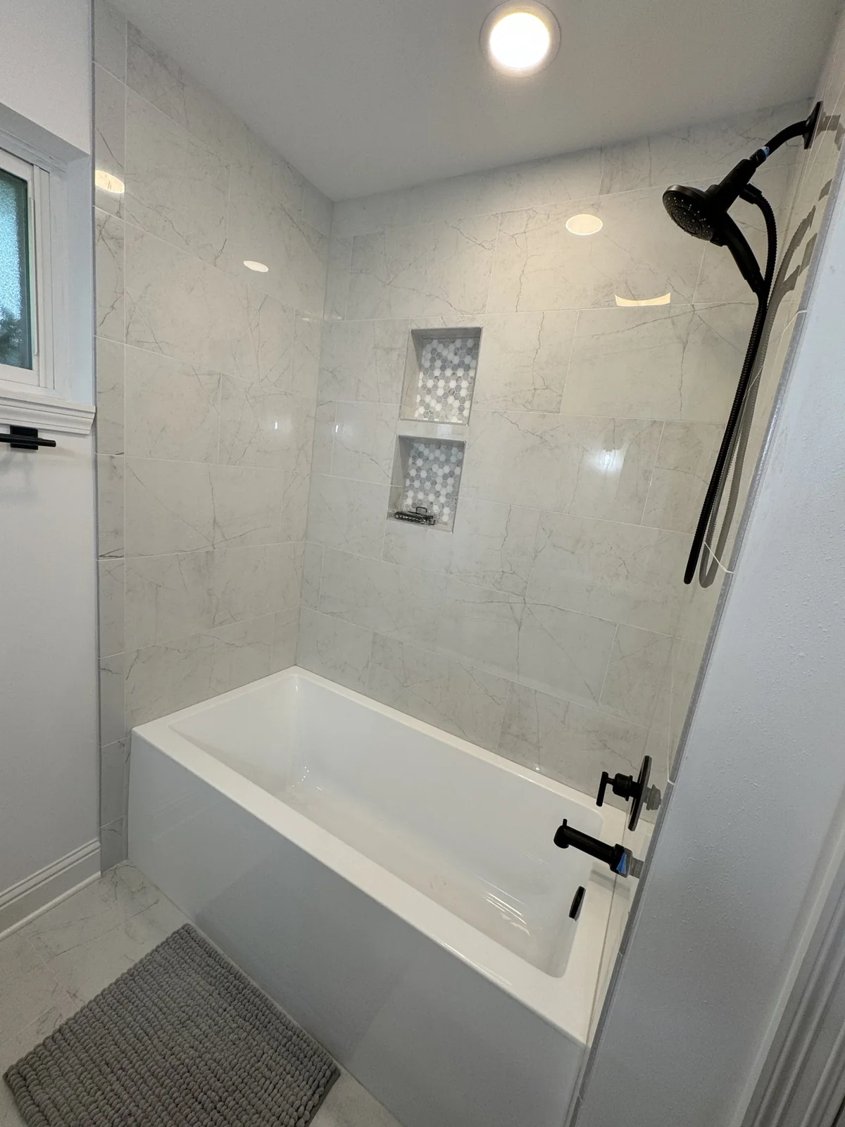 White bathtub with tiled surround and black fixtures