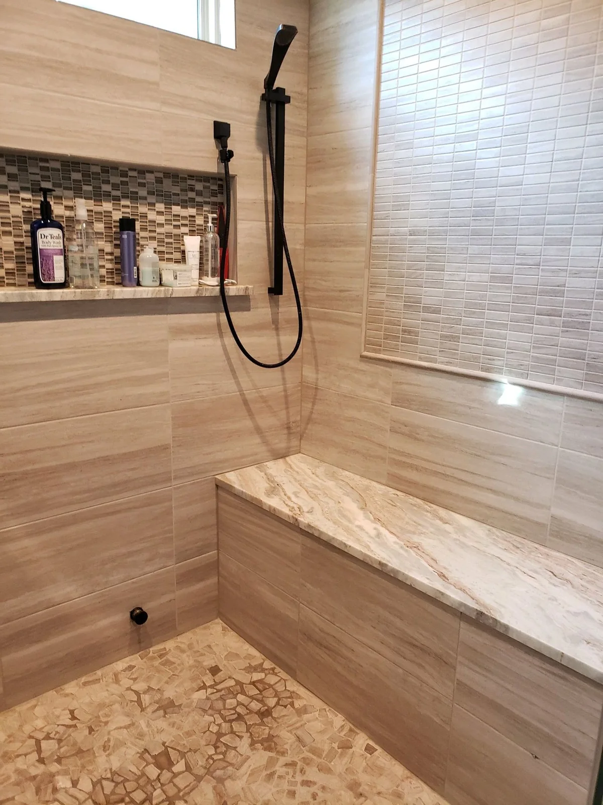 Tiled shower with a built-in bench and niche.