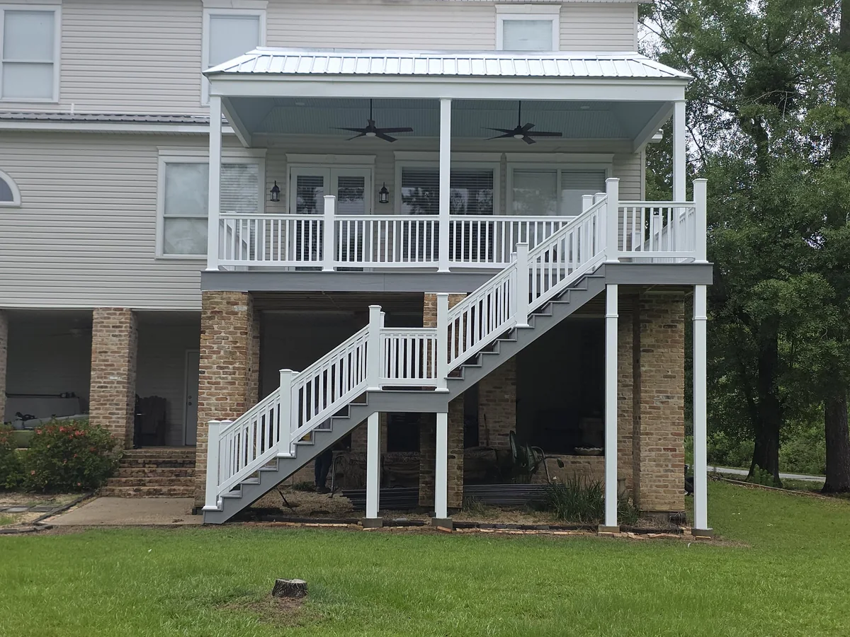 Raised covered back porch with white railings and gray stairs