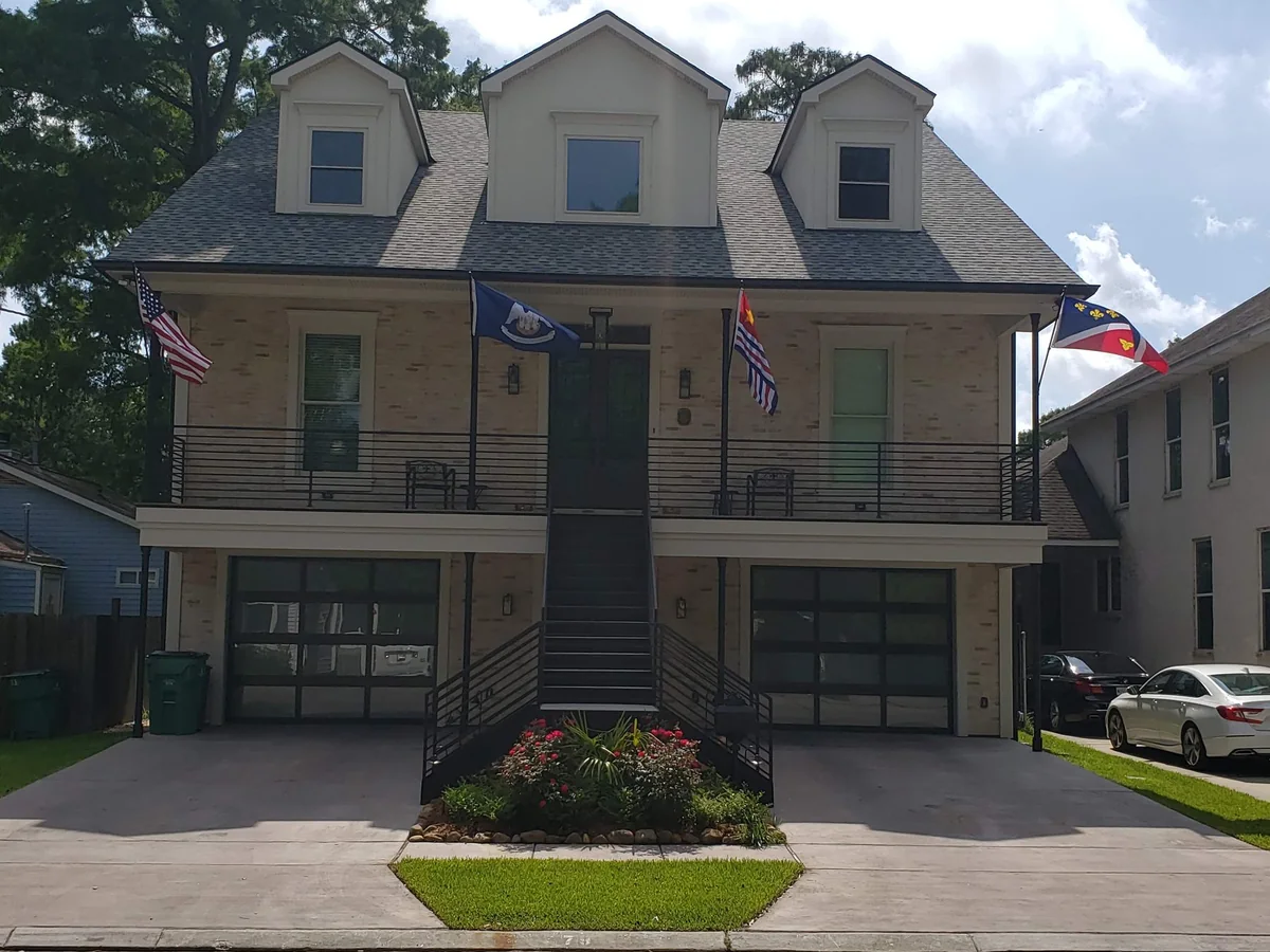 Front exterior of a three-story brick home with a central stair and two ground-level garages.