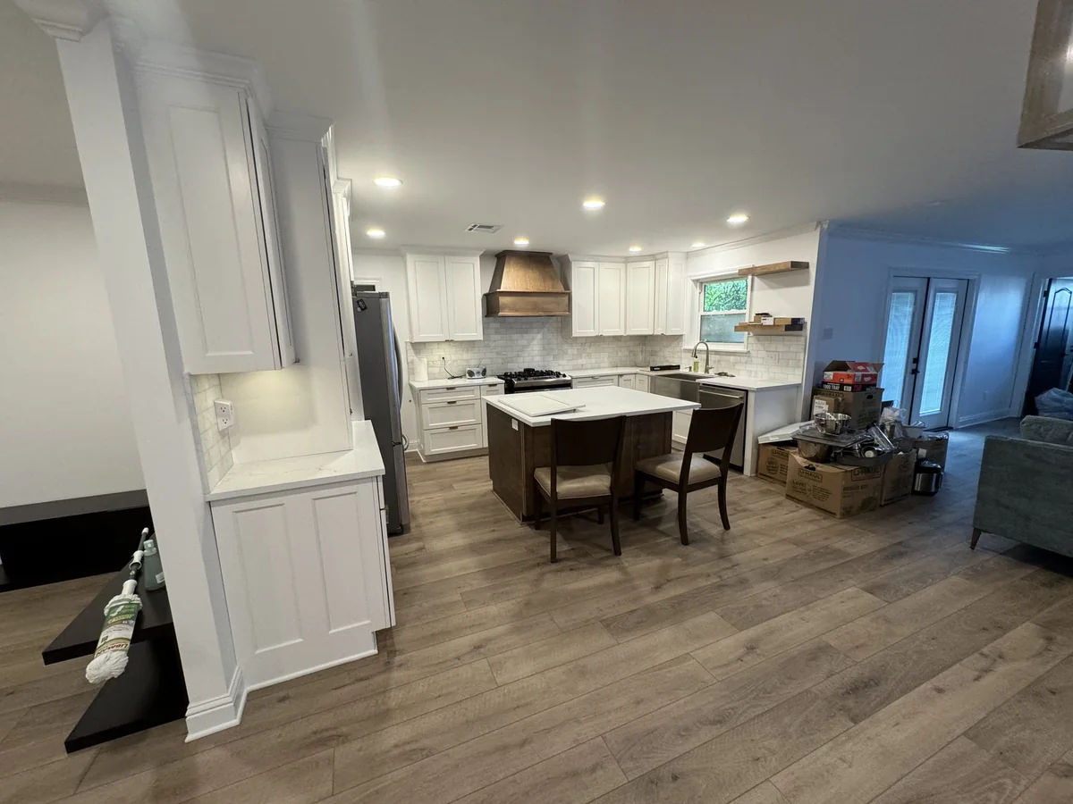 Kitchen with white cabinetry, wood hood and island